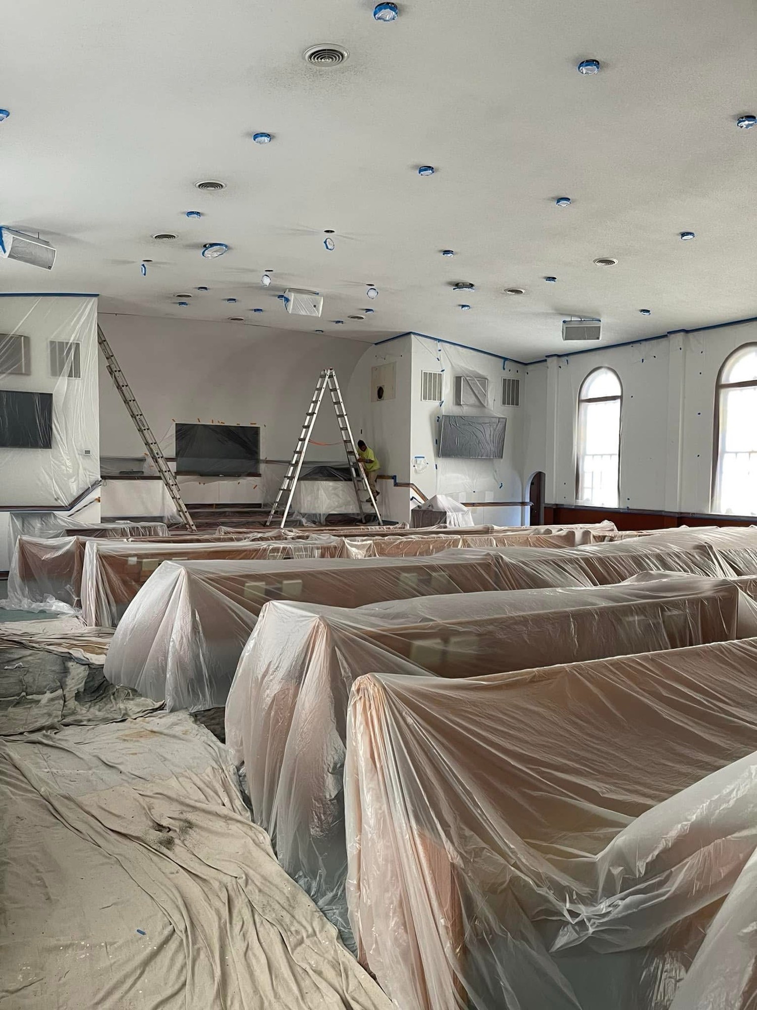 Sanctuary mid-paint with pews covered
