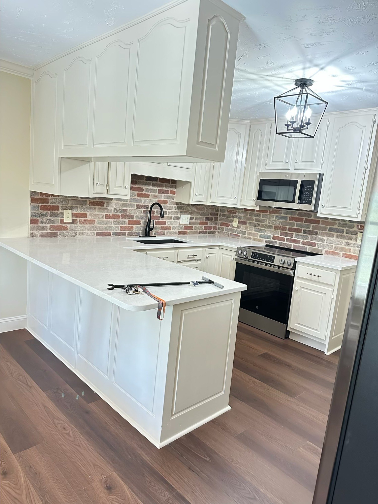 Finished kitchen with cream cabinets and brick backsplash