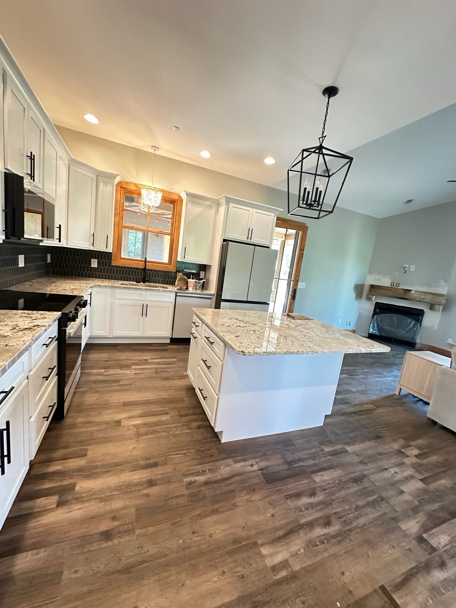 Finished kitchen with white cabinets, island, and wood floors
